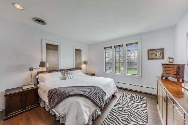 bedroom featuring a baseboard heating unit and dark wood-style floors