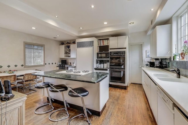 kitchen with open shelves, a sink, black appliances, a kitchen island, and a kitchen bar