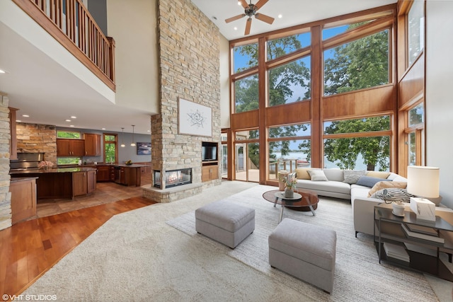 250 Whitney Rd, Lake Zurich, IL 60047 - living room with a high ceiling, a stone fireplace, light wood finished floors, a ceiling fan, and recessed lighting