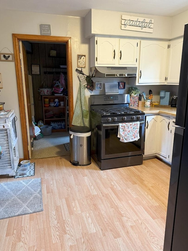 kitchen featuring gas range, under cabinet range hood, light wood finished floors, and white cabinetry