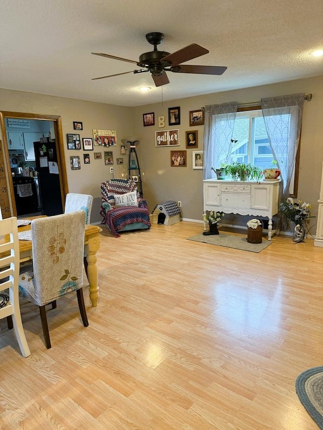 bedroom with black refrigerator, light wood-type flooring, baseboards, a textured ceiling, and ceiling fan