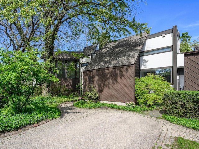 view of side of property featuring a sunroom and roof with shingles
