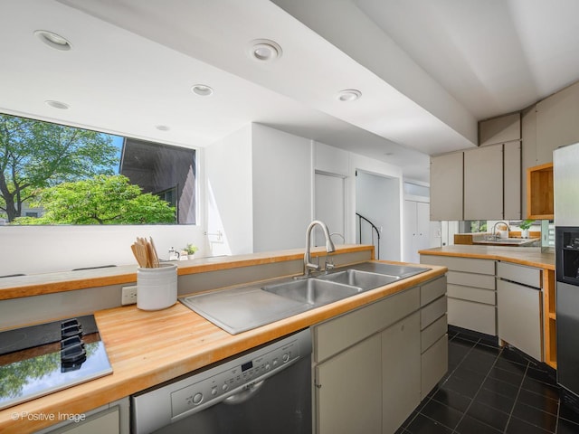kitchen with dishwashing machine, a sink, dark tile patterned flooring, recessed lighting, and stovetop