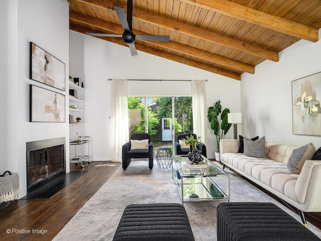 living area with wooden ceiling, a fireplace with flush hearth, wood finished floors, beamed ceiling, and ceiling fan