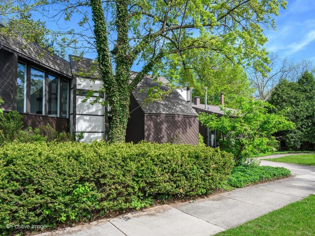 view of property exterior featuring roof with shingles and a sunroom