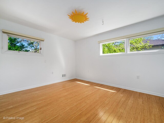 spare room with baseboards and light wood finished floors