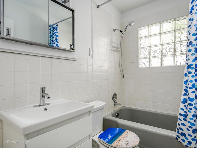 full bath with shower / tub combo, tile walls, toilet, vanity, and decorative backsplash