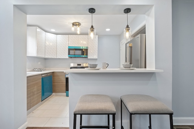 715 E 105th Pl, Chicago, IL 60628 - kitchen featuring stainless steel appliances, light countertops, a breakfast bar, decorative light fixtures, and modern cabinets