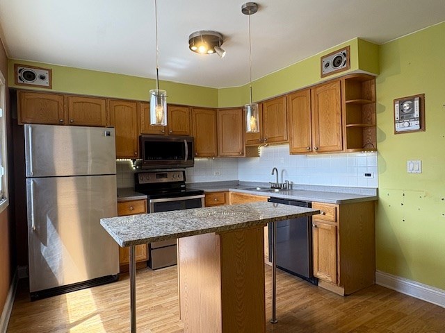 9865 Garden Ct, Schiller Park, IL 60176 - kitchen featuring appliances with stainless steel finishes, light wood-type flooring, baseboards, a sink, and tasteful backsplash