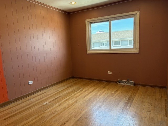 9865 Garden Ct, Schiller Park, IL 60176 - spare room with light wood-type flooring, baseboards, and wood walls