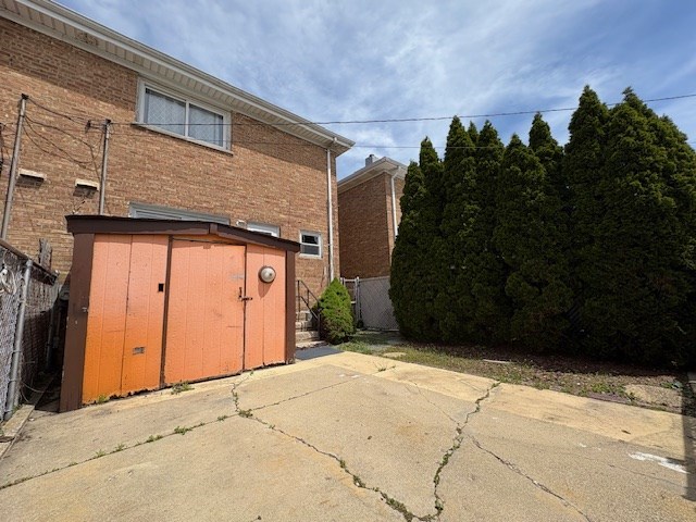9865 Garden Ct, Schiller Park, IL 60176 - back of property featuring a patio, a storage unit, fence, an outbuilding, and brick siding