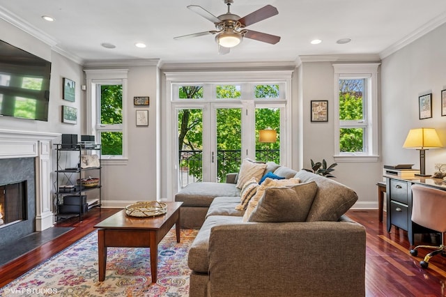 living area featuring a fireplace, a ceiling fan, ornamental molding, dark wood-style floors, and baseboards