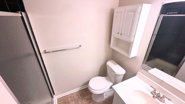 bathroom featuring an enclosed shower, toilet, vanity, and baseboards