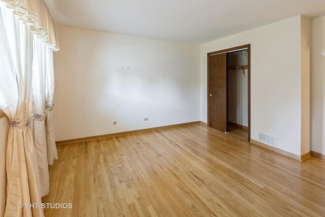 1527 W Amelia Ln, Addison, IL 60101 - unfurnished bedroom with light wood finished floors, baseboards, and a closet