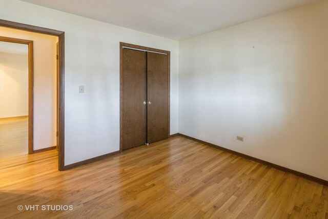 1527 W Amelia Ln, Addison, IL 60101 - unfurnished bedroom with baseboards, light wood-style flooring, and a closet