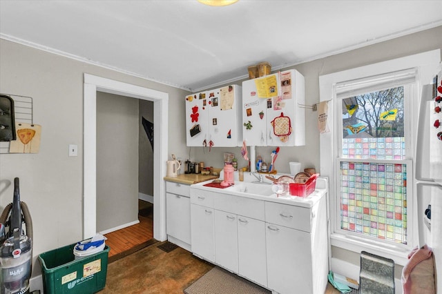 401 S Maple St, Urbana, IL 61801 - kitchen with light countertops, a sink, white cabinetry, and crown molding