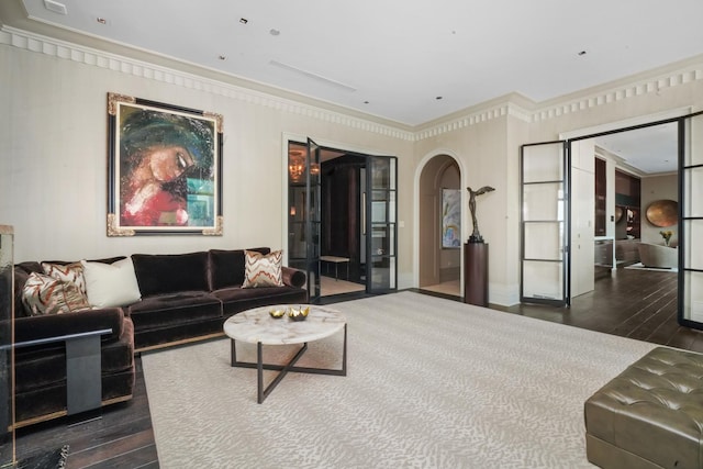 living area with dark wood-style floors, arched walkways, and ornamental molding