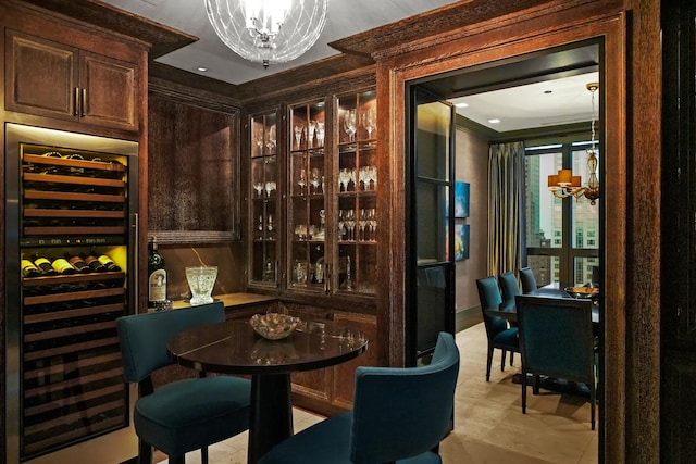 wine area with wine cooler, a chandelier, ornamental molding, baseboards, and light tile patterned floors