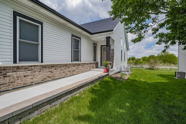 570 Sudbury Cir, Oswego, IL 60543 - view of side of property with a lawn, brick siding, roof with shingles, and central AC unit
