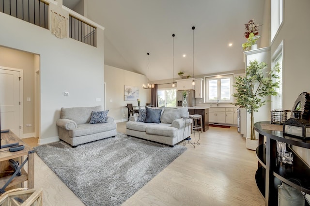 570 Sudbury Cir, Oswego, IL 60543 - living area with high vaulted ceiling, light wood-type flooring, a chandelier, and baseboards