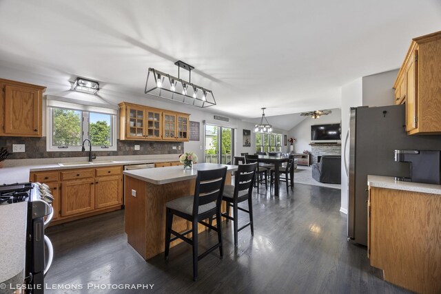 kitchen with stainless steel appliances, a sink, plenty of natural light, tasteful backsplash, and vaulted ceiling