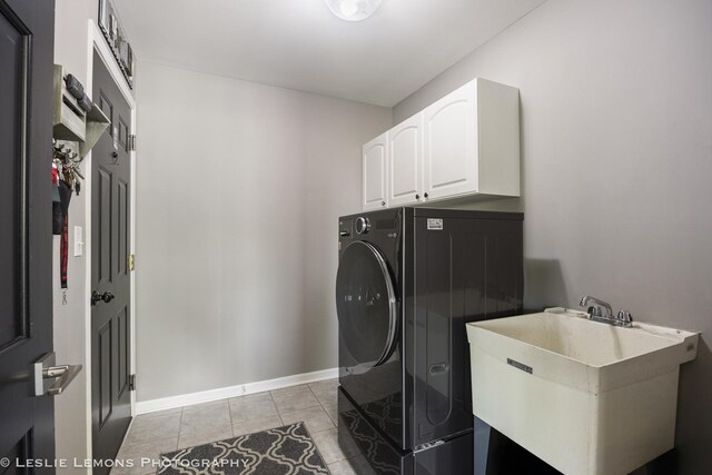 washroom featuring washer / dryer, cabinet space, light tile patterned floors, and baseboards