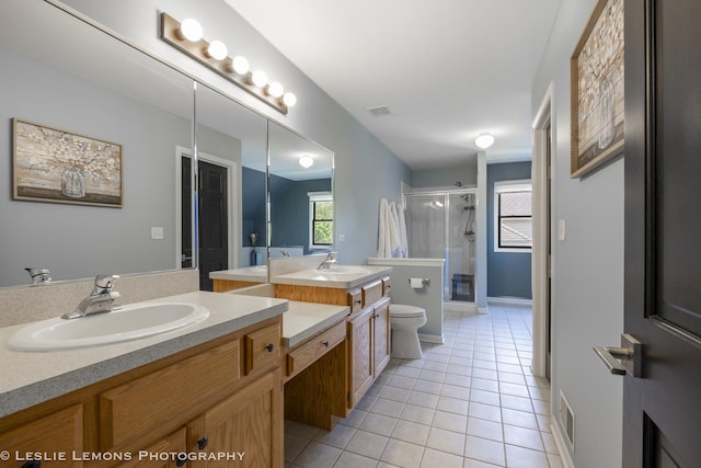 bathroom featuring tile patterned flooring, a stall shower, toilet, and two vanities