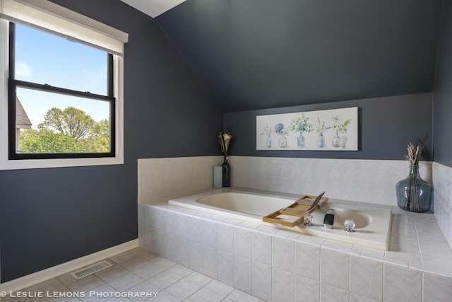 full bath featuring lofted ceiling, tile patterned floors, a bath, and baseboards