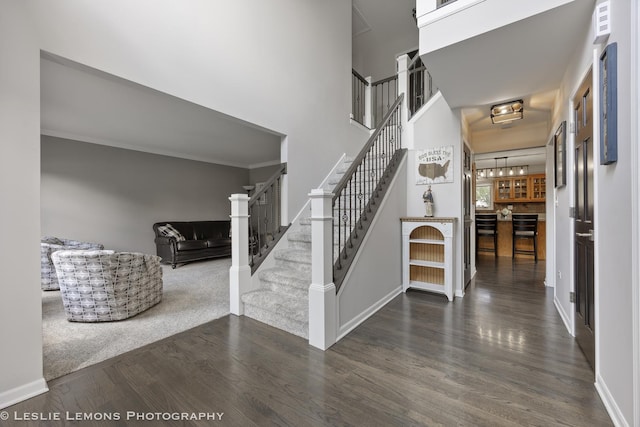 stairway featuring wood finished floors, a high ceiling, and baseboards