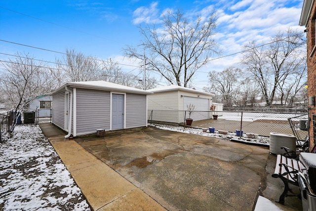 14821 Cooper Ave, Harvey, IL 60426 - snow covered patio featuring an outbuilding, fence, a detached garage, a gate, and cooling unit