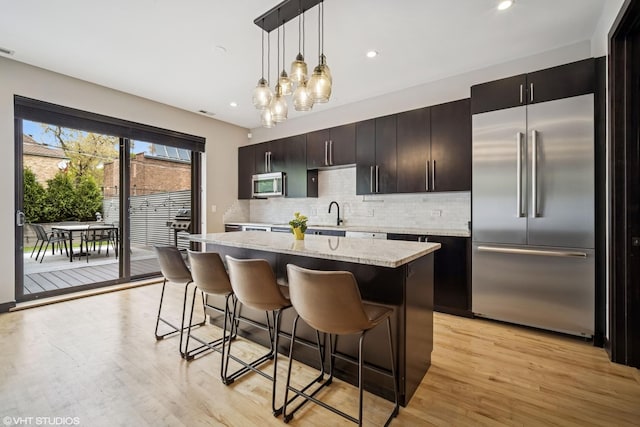 2130 W N Ave Unit 208, Chicago, IL 60647 - kitchen with stainless steel appliances, a kitchen island, decorative backsplash, a breakfast bar, and recessed lighting