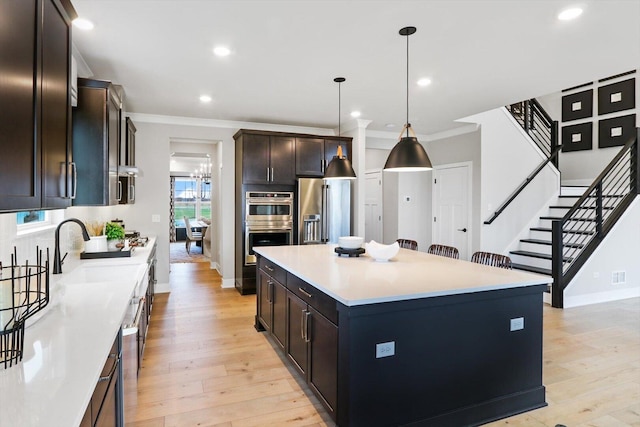 617 Henry Ln, Oswego, IL 60543 - kitchen with appliances with stainless steel finishes, baseboards, ornamental molding, a kitchen island, and light wood finished floors