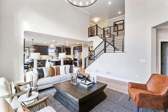 617 Henry Ln, Oswego, IL 60543 - living area featuring stairs, a chandelier, light wood-style floors, recessed lighting, and a towering ceiling