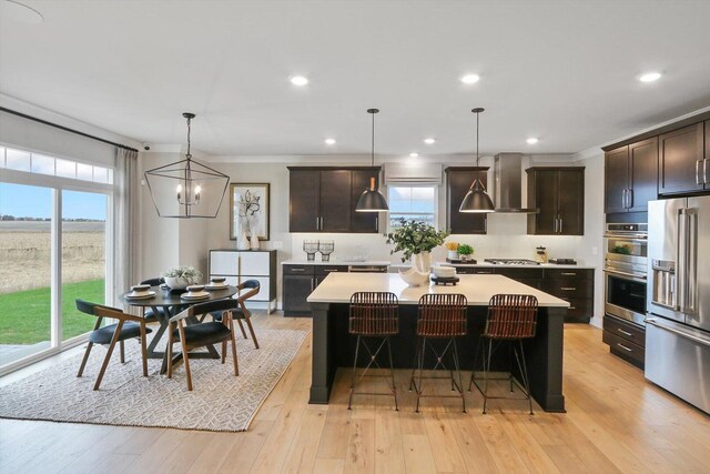 617 Henry Ln, Oswego, IL 60543 - kitchen featuring stainless steel appliances, wall chimney range hood, light countertops, a center island, and dark brown cabinets