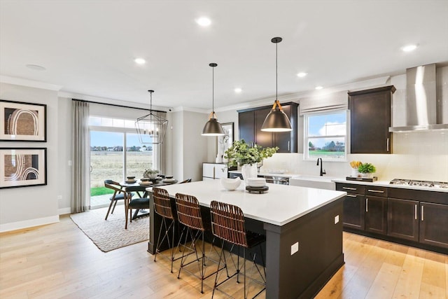 617 Henry Ln, Oswego, IL 60543 - kitchen featuring wall chimney range hood, a center island, tasteful backsplash, a breakfast bar, and crown molding