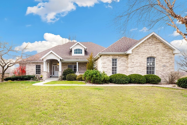 view of front of property with brick siding, a front lawn, and a shingled roof