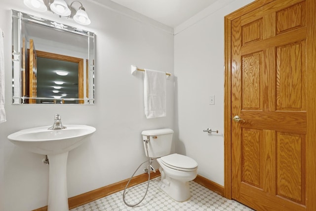 half bathroom with toilet, baseboards, and a sink