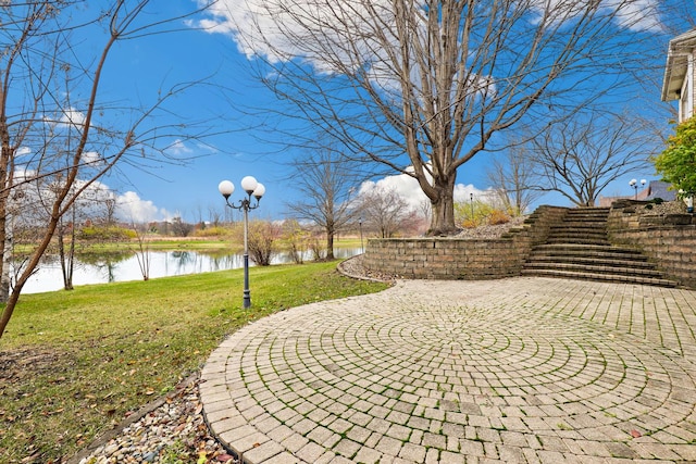 view of property's community with a water view, a yard, and a patio area