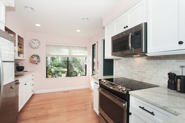 kitchen featuring appliances with stainless steel finishes, white cabinets, backsplash, baseboards, and light stone countertops