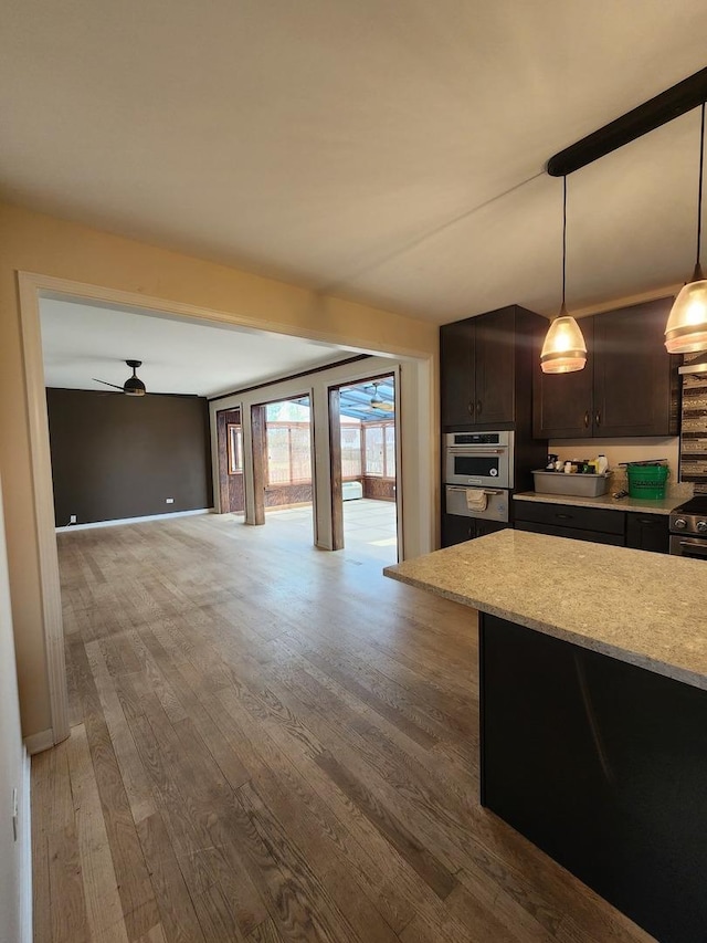 kitchen featuring oven, a warming drawer, open floor plan, hanging light fixtures, and wood finished floors
