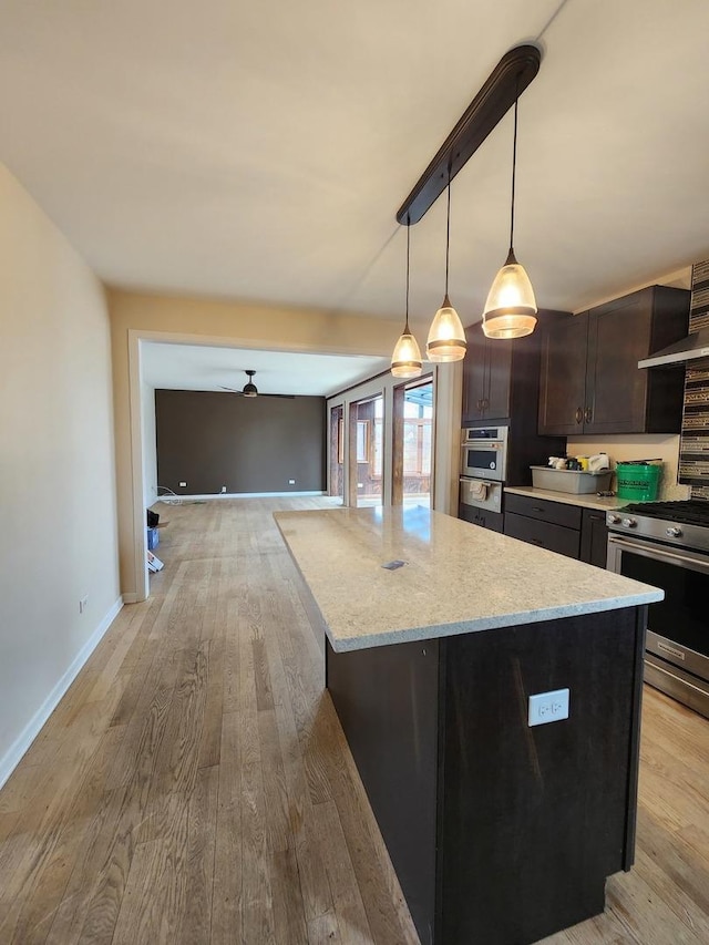 kitchen featuring stainless steel appliances, light wood-type flooring, dark brown cabinets, and a kitchen island
