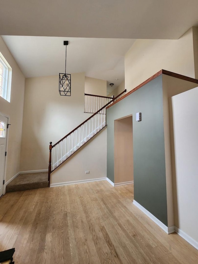 entrance foyer with light wood-style flooring, baseboards, and stairs