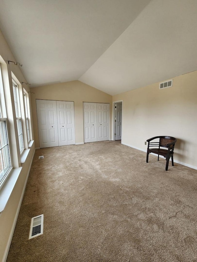 unfurnished bedroom with two closets, baseboards, carpet flooring, and vaulted ceiling