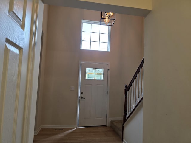 foyer featuring wood finished floors, a chandelier, baseboards, and stairway