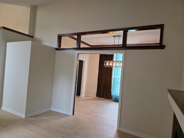 spare room featuring light wood-type flooring, baseboards, and a chandelier