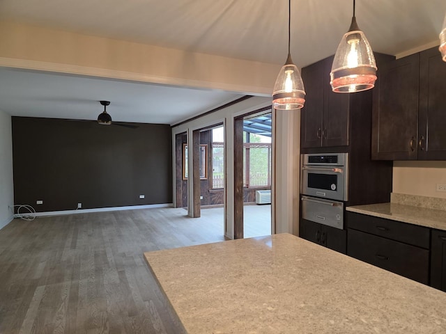 kitchen featuring oven, wood finished floors, a warming drawer, a ceiling fan, and dark brown cabinetry