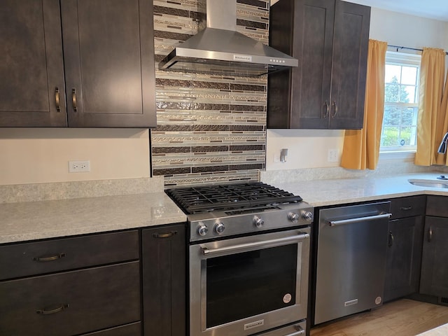 kitchen with wall chimney range hood, stainless steel appliances, light countertops, and decorative backsplash