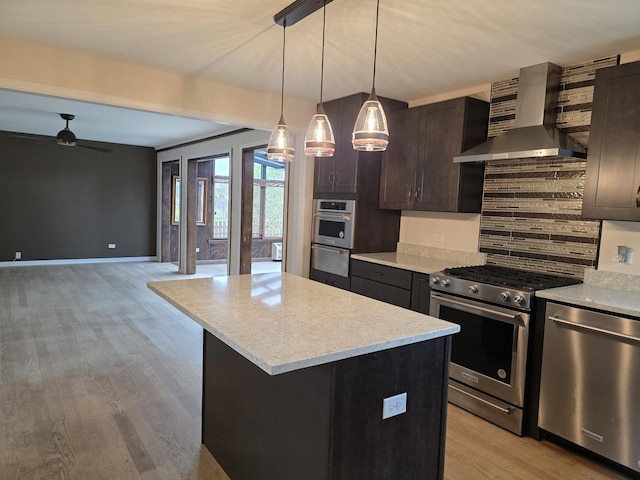 kitchen with wall chimney range hood, stainless steel appliances, a ceiling fan, light wood-type flooring, and dark brown cabinets