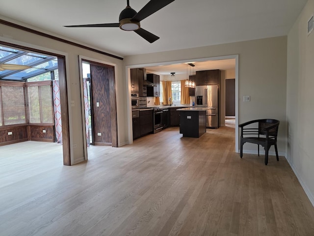living room with a chandelier, light wood finished floors, a ceiling fan, and baseboards