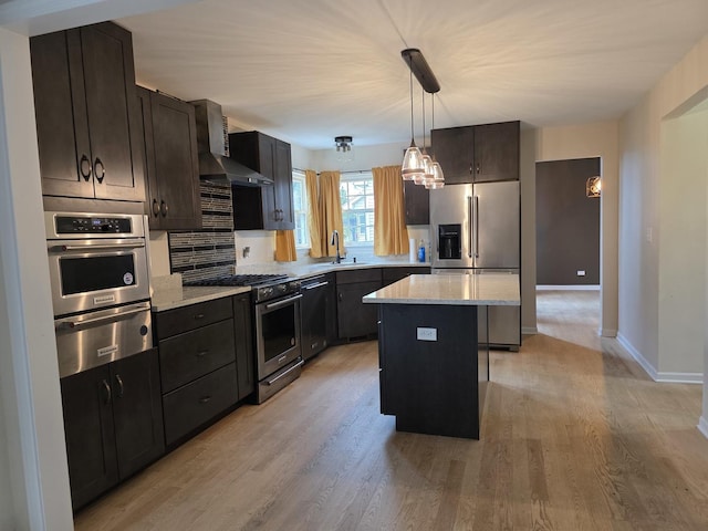 kitchen with appliances with stainless steel finishes, wall chimney exhaust hood, a warming drawer, a sink, and a center island